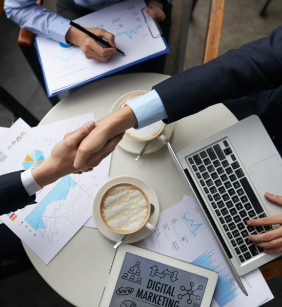 Business people shaking hands overtable with documents